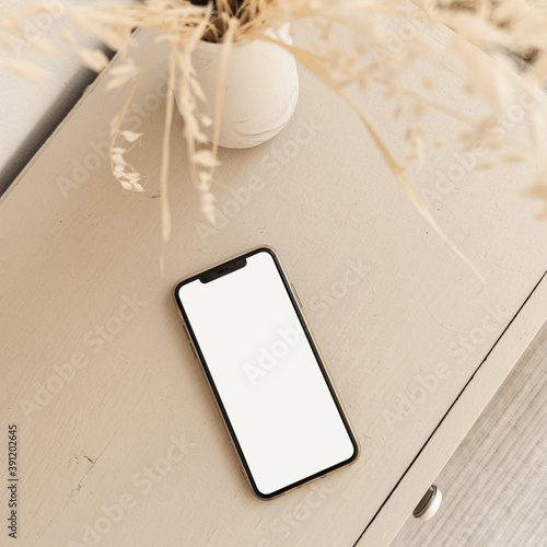 Blank screen smart phone on beige pastel table. Flat lay, top view. Copy space mockup template.