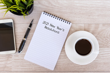 Wall Mural - 2021 New Year's Resolutions text on note pad with smart phone and cup of coffee