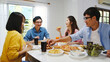 © tirachard - Happy young friends group having lunch at home. Asia family party eating pizza food and laughing enjoying meal while sitting at dining table together at house. Celebration holiday and togetherness.