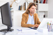 © JackF - Woman in disposable face mask working in business office using laptop