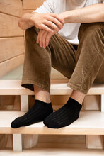 Thinking Man Sits On A Wooden Ladder In Socks.