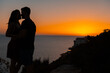 © MinekPSC - Young couple kiss each other at sunset from a cliff overlooking the sea