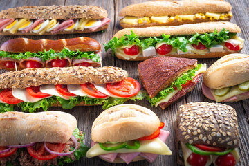 Poster - Assorted sandwiches on wooden background.