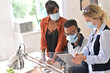 © goodluz - Coworkers in open space office, wearing surgical face mask 19-ncov pandemic