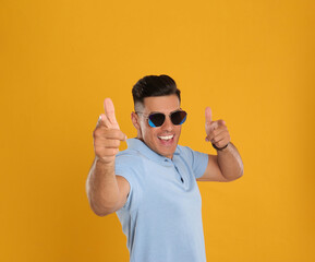 Wall Mural - Excited man wearing sunglasses on yellow background