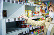 © Kalim - Adult woman in medical mask in front of empty shelves in grocery store