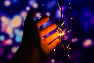 Wall Mural - A man tries to catch sparkles from a sparkler beautiful photo on a bright background new year and christmas holiday