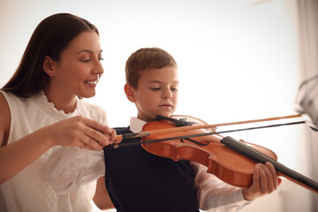 Canvas Print - Young woman teaching little boy to play violin indoors