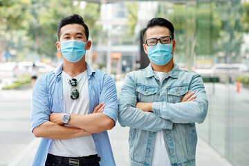 Sticker - Serious confident young Asian men standing outdoors with arms folded and looking at camera