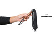 Leather whip in male hand good isolated on white background. Strict black whip in man's hand. Accessories for adult sexual games. Toys for BDSM, flogging, sexual fetish and spanking devices.Copy space