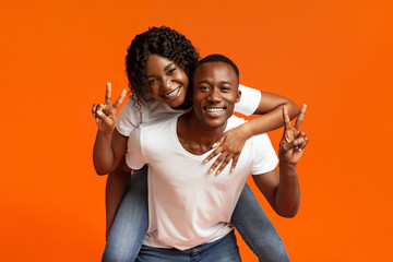 Happy black lovers posing on orange studio background