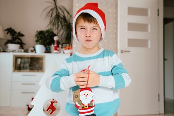 Horizontal view of caucasian little kid with angry expression at Christmas time at home. Joy and family lifestyle with kids at seasonal december Christmas. Santa Claus and gift giving concept.