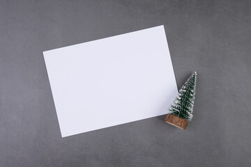 Wall Mural - Christmas holiday composition decoration with pine tree and blank postcard mockup on cement floor background, new year and xmas or anniversary on concrete in season, top view or flat lay, copy space.