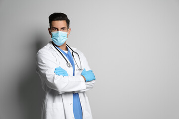 Wall Mural - Doctor in protective mask and medical gloves against light grey background. Space for text