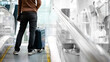 © zephyr_p - Travel insurance concept. Male tourist or passenger man carrying suitcase luggage and digital tablet on travelator or moving walkway in airport terminal.