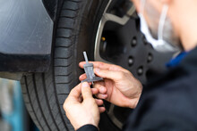 Mechanic Checking Checking The Depth Of Car Tire Tread.  Car Maintenance And Auto Service Garage Concept.