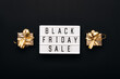 Lightbox with text BLACK FRIDAY SALE and golden gift boxes on black background