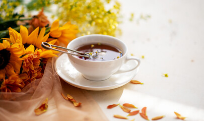 Autumn, fall leaves, flowers hot cup of herbal tea on wooden rustic background. Seasonal, morning tea. Sunday relaxing and still life concept. Toned image. Copy space.