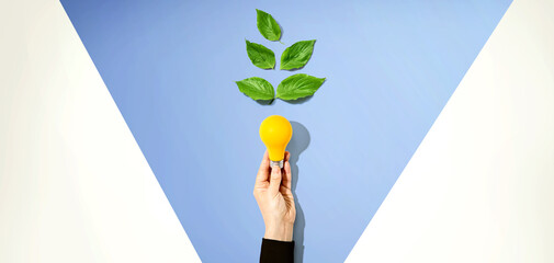 Person holding a light bulbs with green leaves