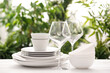 © New Africa - Set of clean dishware and wineglasses on white table against blurred background