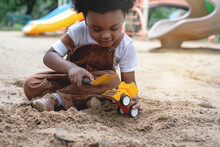 Dark-skinned Boy Enjoy Playing With Toy Cars And Sand At Playground