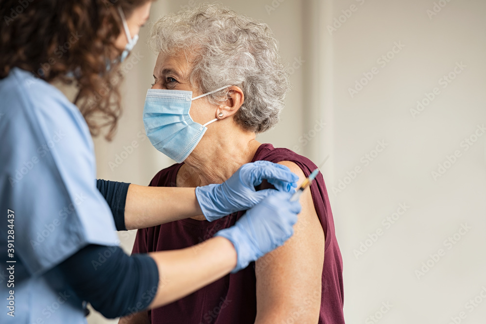 Doctor giving Covid vaccine to senior woman - obrazy, fototapety, plakaty 