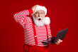 © deagreez - Photo of retired grandfather grey beard hold laptop shock hand head forget fulfill kid wish wear santa x-mas costume suspenders spectacles striped shirt cap isolated red color background