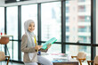 Asian Muslim businesswoman in hijab head scarf working with paper document in the modern office. businesspeople, diversity and office concept