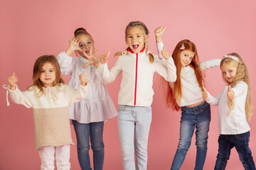 thumbs up. portrait of little caucasian children isolated on pink studio background with copyspace. 