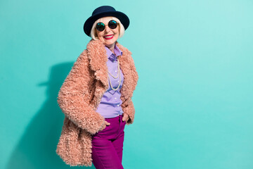 Poster - Photo of charming old woman dressed vintage outerwear cap eyewear smiling isolated turquoise color background