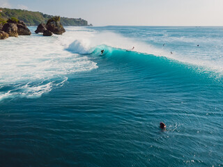 Aerial view with surfing at barrel wave. Blue perfect waves and surfer