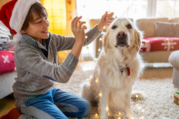 Wall Mural - Boy and his dog enjoying Christmas together at home 
