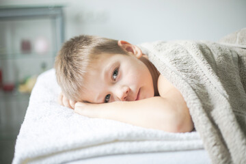 Wall Mural - Professional  Physiotherapist is treating a kid in clinic. Boy toddler relaxes from a therapeutic massage.