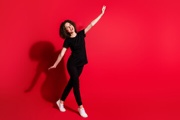 Wall Mural - Full length body size photo of young happy smile woman hands fly walk empty space isolated over red color background