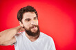 © SHOTPRIME STUDIO - A man in a white T-shirt with a beard gestures with his hands emotions red background