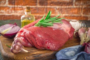 Wall Mural - Raw meat, beef fillet, large piece on a cutting board with spices for cooking. Black dark green background, copy space