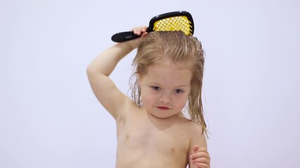 cute little blonde girl combing her hair with a yellow comb on white background. hair care. fullhd f