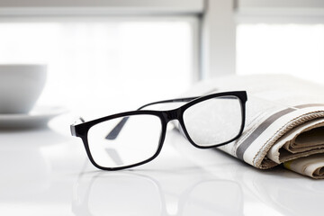 Newspapers and coffee cup, with reading glasses. 