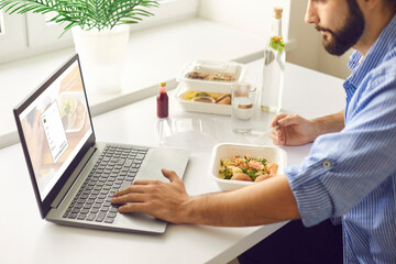 Man having takeaway meal and signing up for food delivery website during lunch break in office