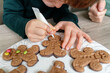 © beavera - Horizontal detail of unrecognizable children decorating ginger cookies in the kitchen. Christmas recipe of traditional sweet chocolate desserts for the festivities. Lifestyle with kids at home.