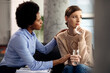 Depressed woman being consoled by her psychotherapist during a session.