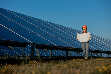 Handsome Architect Woman Examining a Draft Map or Blueprint Project Plan, Worker Activity Looking Out in Photovoltaic Cell Farm or Solar Panels Field