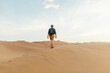 © Carter Wright/Stocksy - Blonde man facing away in flannel travels across sand dunes in the desert while traveling on an adventure