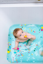 Sensory Bath Time Play For A Baby And Toddler With Colorful Pompons And Blue Water