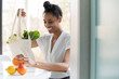 © jamie grill photography/Stocksy - Woman unpacking reusable tote bag full of groceries
