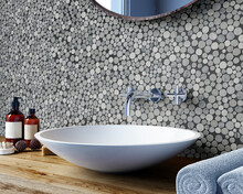 Interior Of A Modern Bathroom With A Wall With A Round Mosaic Of Grey Shades. Round Mirror And Washbasin On A Wooden Shelf. Spa Treatments. 3d Rendering