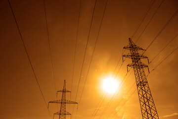 Background of Pylon and power lines at sunset with red sky with clouds and sun shine rays