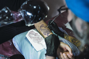 Canvas Print - Tattoo artist tattooing a dragon on a man's arm