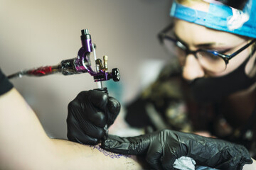 Canvas Print - Female tattoo artist tattooing a dragon on a man's arm