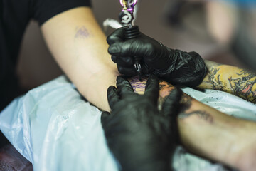 Tattoo artist tattooing a dragon on a man's arm